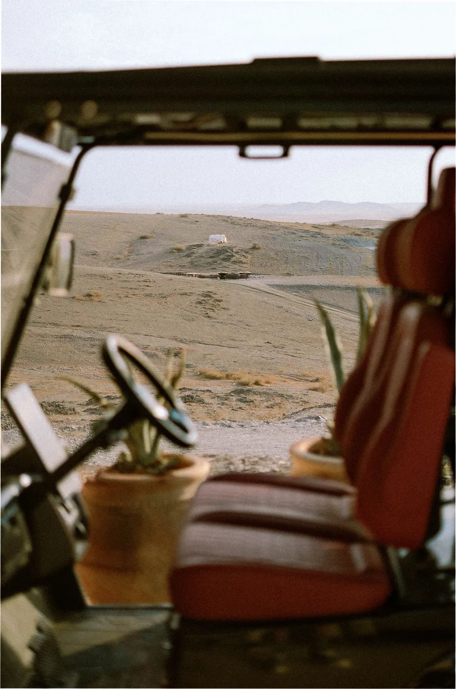 Uitzicht vanuit een open terreinwagen op een zandweg die de verte in loopt.