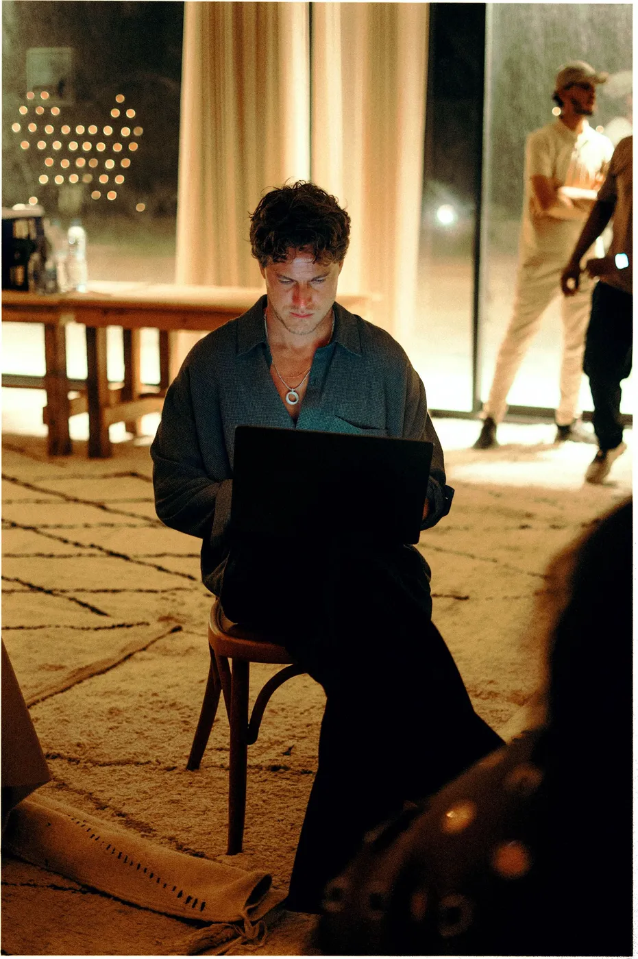 Een deelnemer zit 's avonds alleen op een stoel in de tent en werkt op zijn laptop.